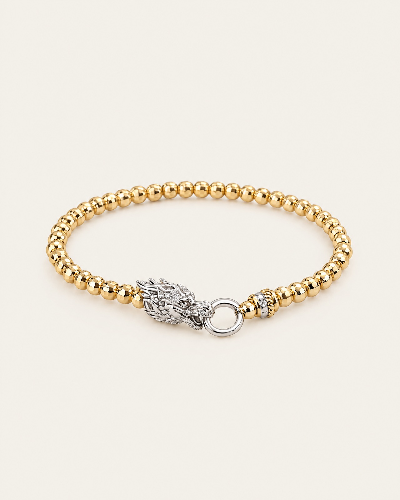 The gold-tone beaded dragon bracelet with polished beads and a silver-tone dragon head, on a light background