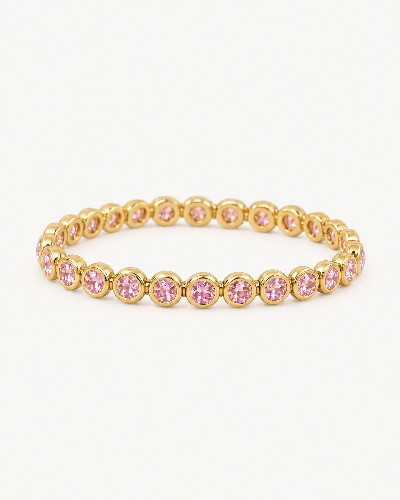 The pink round-stone bracelet with faceted pink stones in smooth gold-tone bezels, on a light background