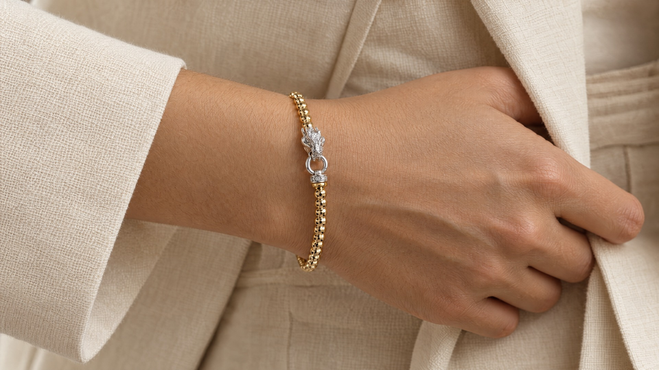 The gold-tone beaded dragon bracelet worn on a wrist