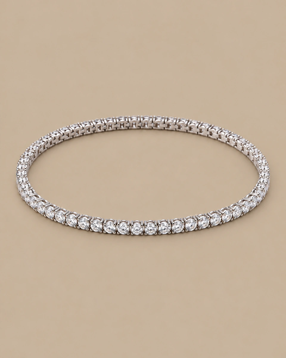 The clear tennis bracelet with round stones and silver-tone settings, on a warm beige background