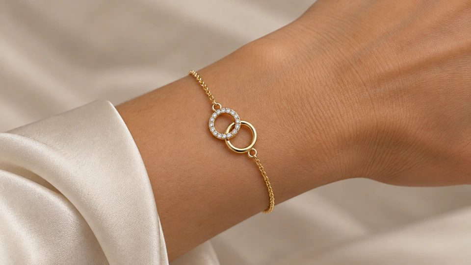 The gold-tone circle bracelet worn on a wrist beside an ivory sleeve