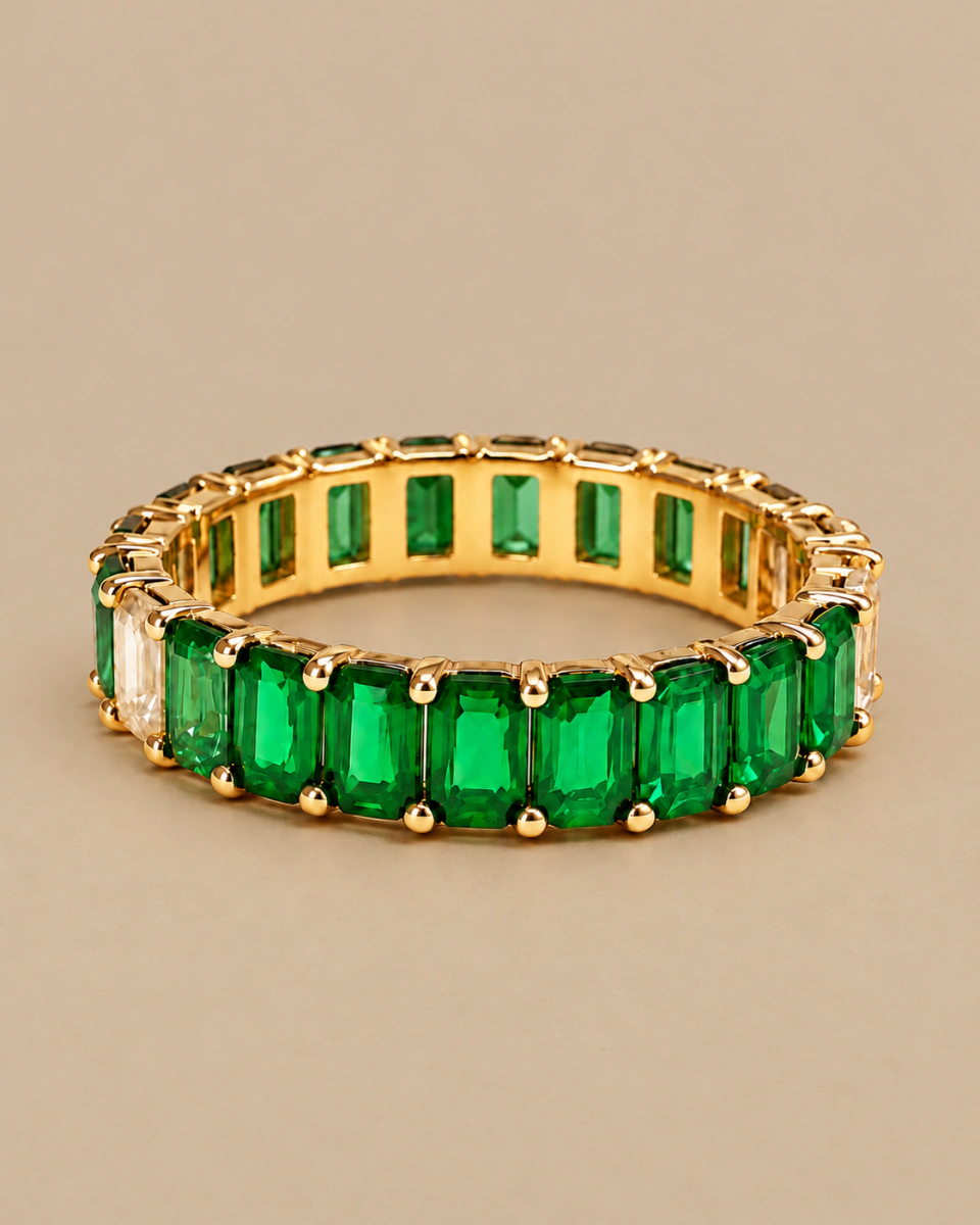 The green ring with green stones and pale details at both sides, on a warm beige background