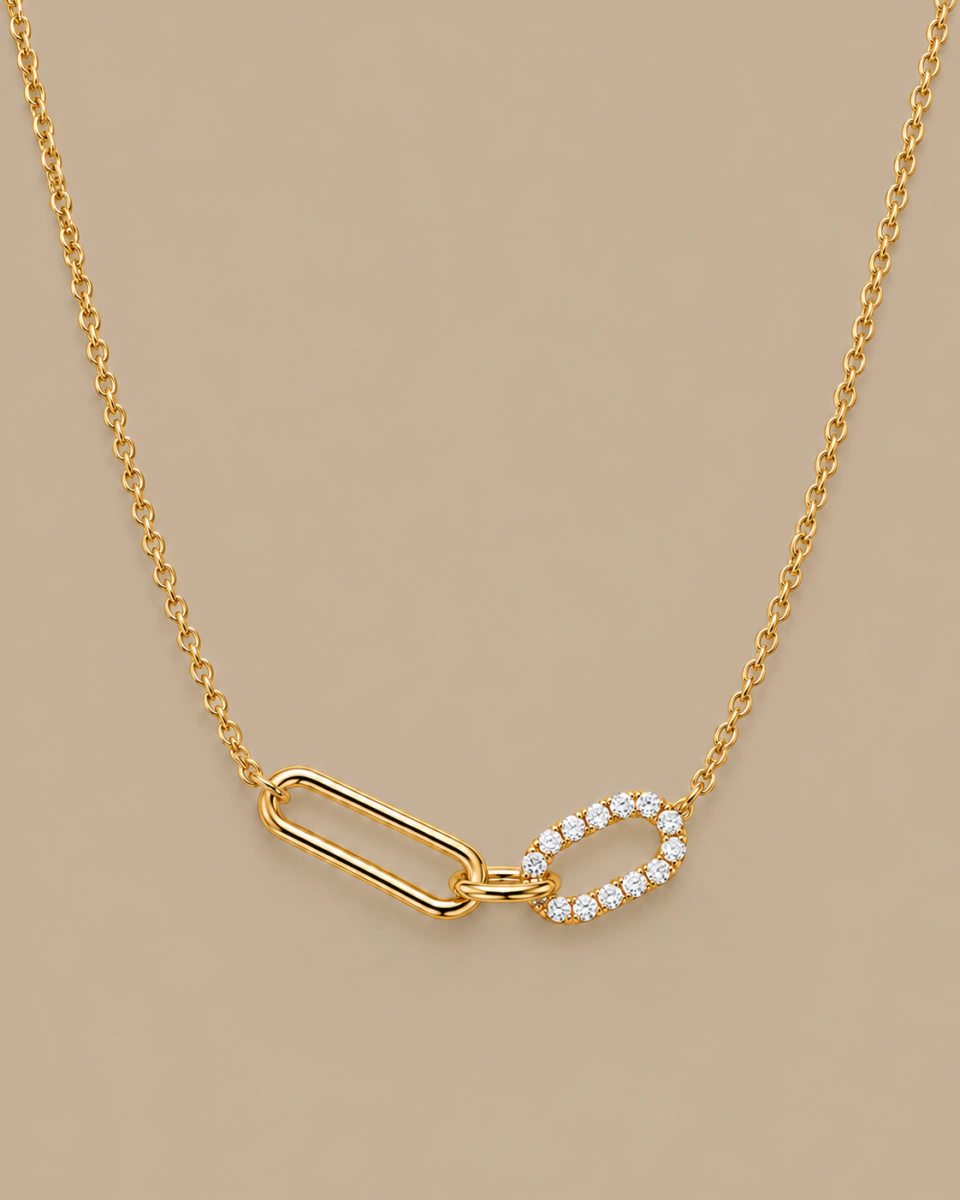 The oval-link necklace with its small connecting link and clear-stone oval, on a warm beige background