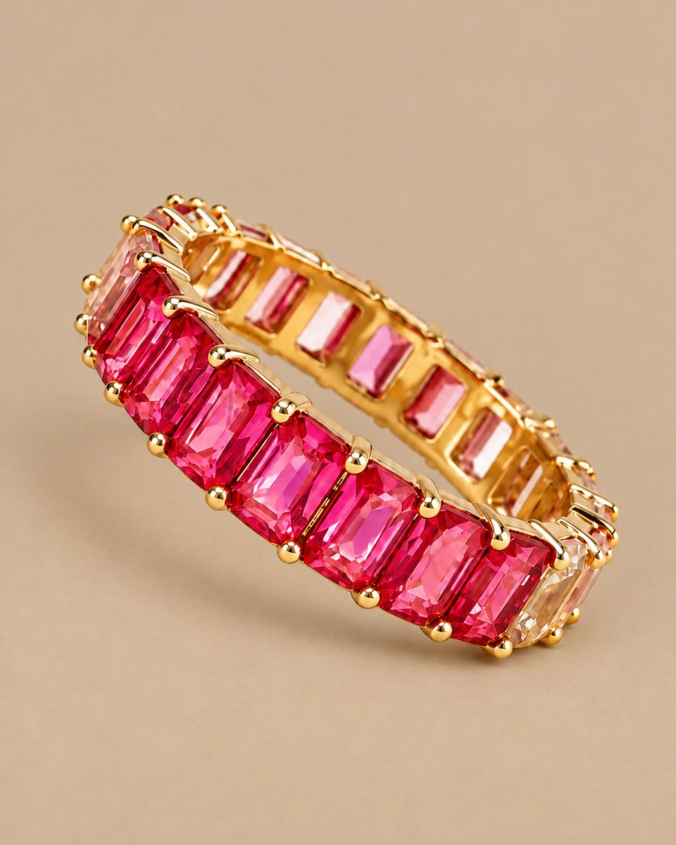The pink ring with rectangular stones and an open gold-tone setting, on a warm beige background