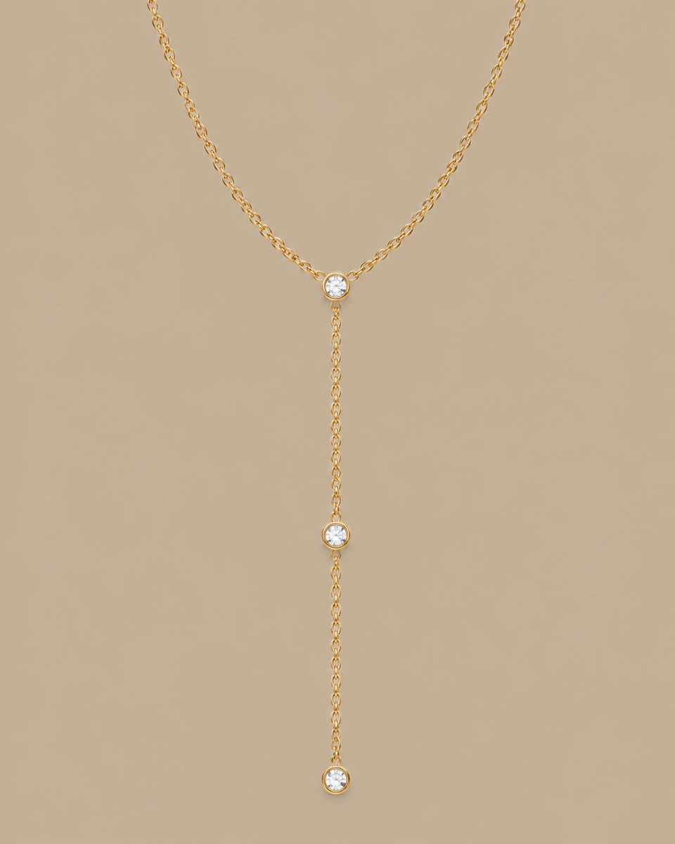 The three-stone lariat with its complete vertical drop, on a warm beige background