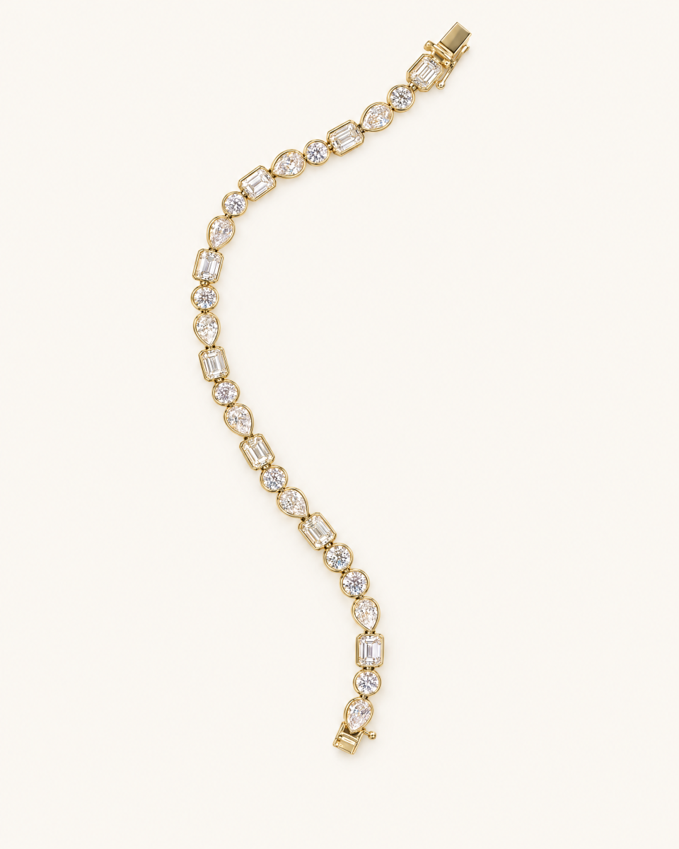 The mixed-shape bracelet with clear rectangular, round and pear-shaped stones in gold-tone settings, on a light background