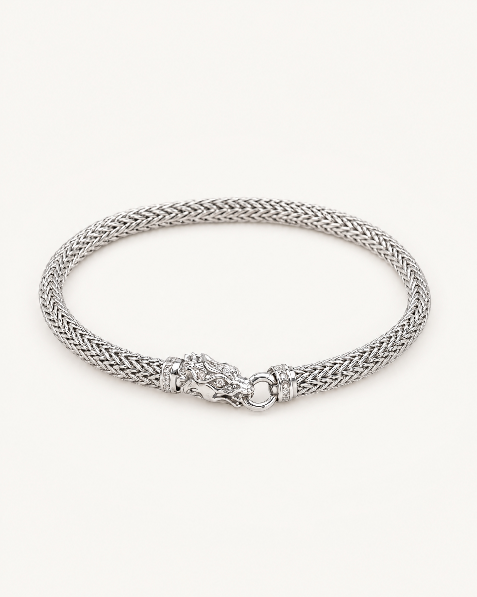 The silver-tone dragon bracelet with a woven chain and sculpted animal-head clasp, on a light background